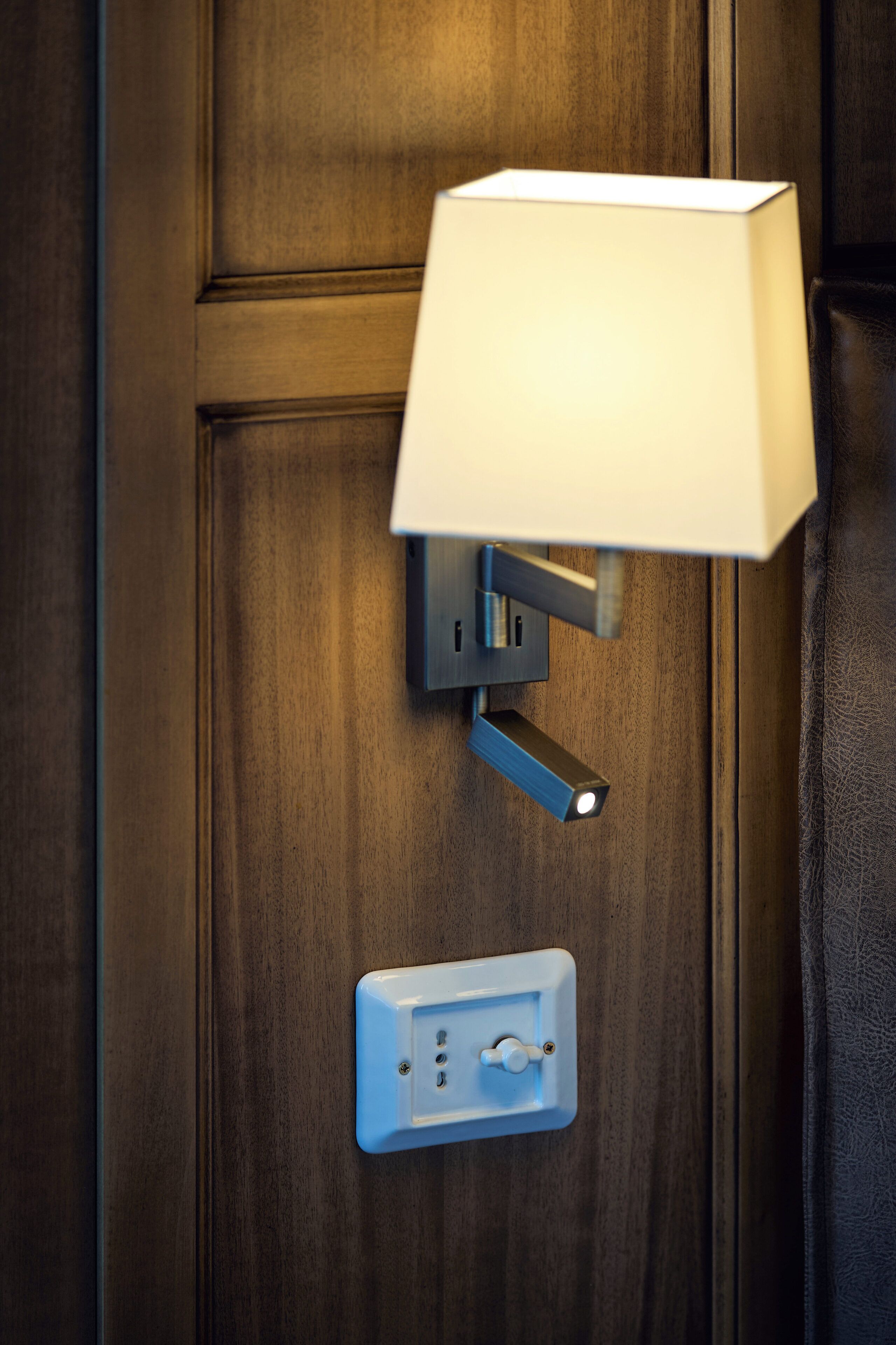 Un luminaire mural, fixé au mur, avec un interrupteur et une prise de courant, le tout installé sur une porte en bois.