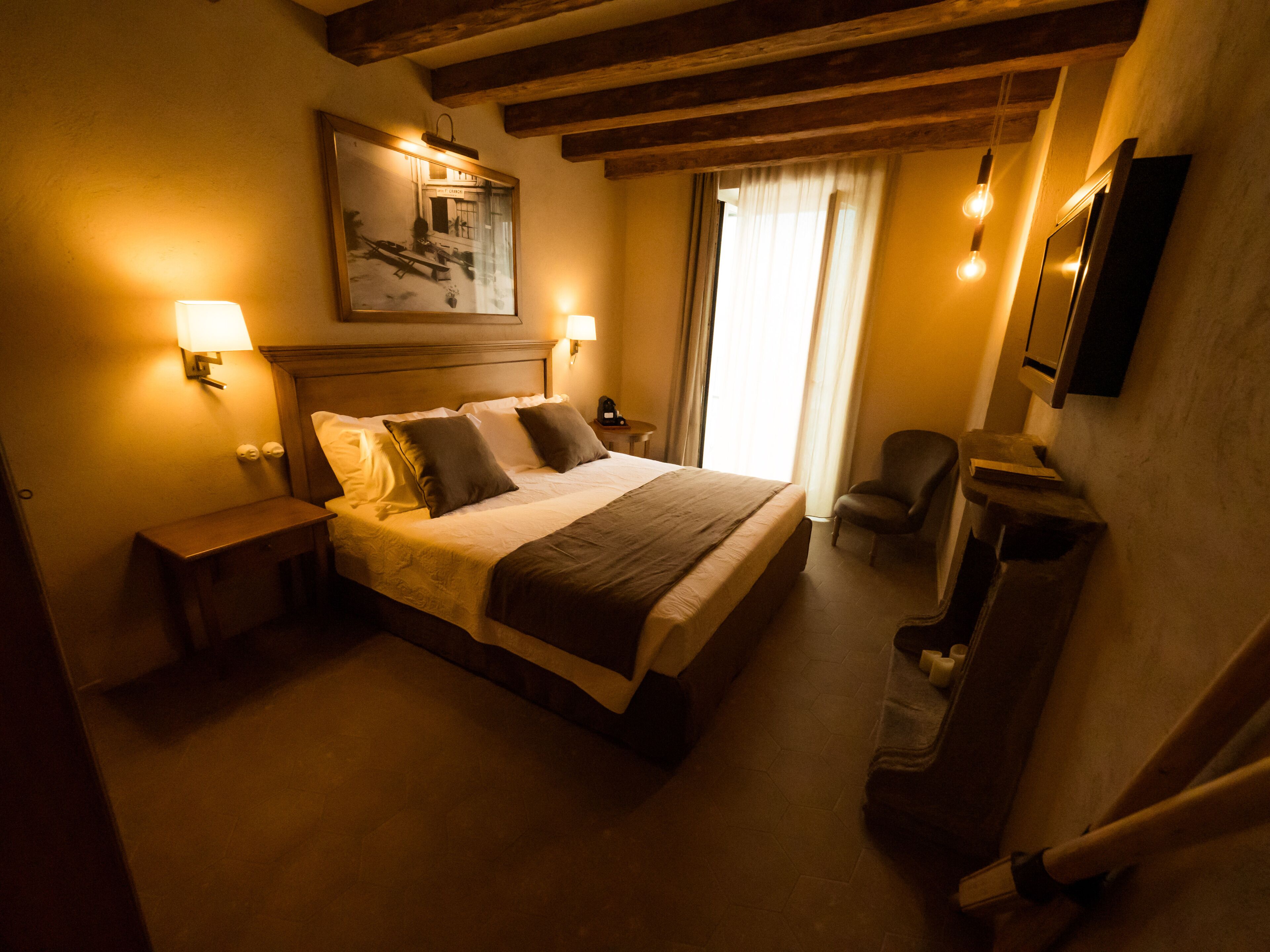 Une chambre d’hôtel avec un grand lit, des lampes de chevet, une chaise, un bureau et un tableau au mur.