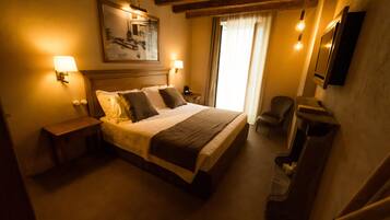 Une chambre d’hôtel avec un grand lit, des lampes de chevet, une chaise, un bureau et un tableau au mur.
