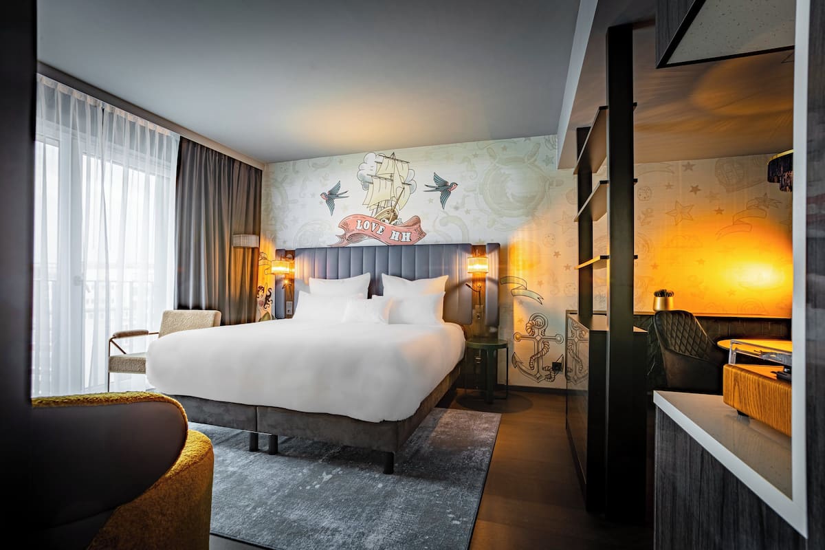 Quarto de hotel moderno com uma cama grande, uma escrivaninha e uma cadeira.