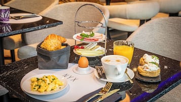 Een ontbijt met roerei, toast, een sandwich en een drankje op een tafel.