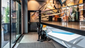 A modern interior with a glass partition, a black cat sculpture, and abstract wall art. - NYX Hotel Hamburg by Leonardo Hotels (Hamburg)
