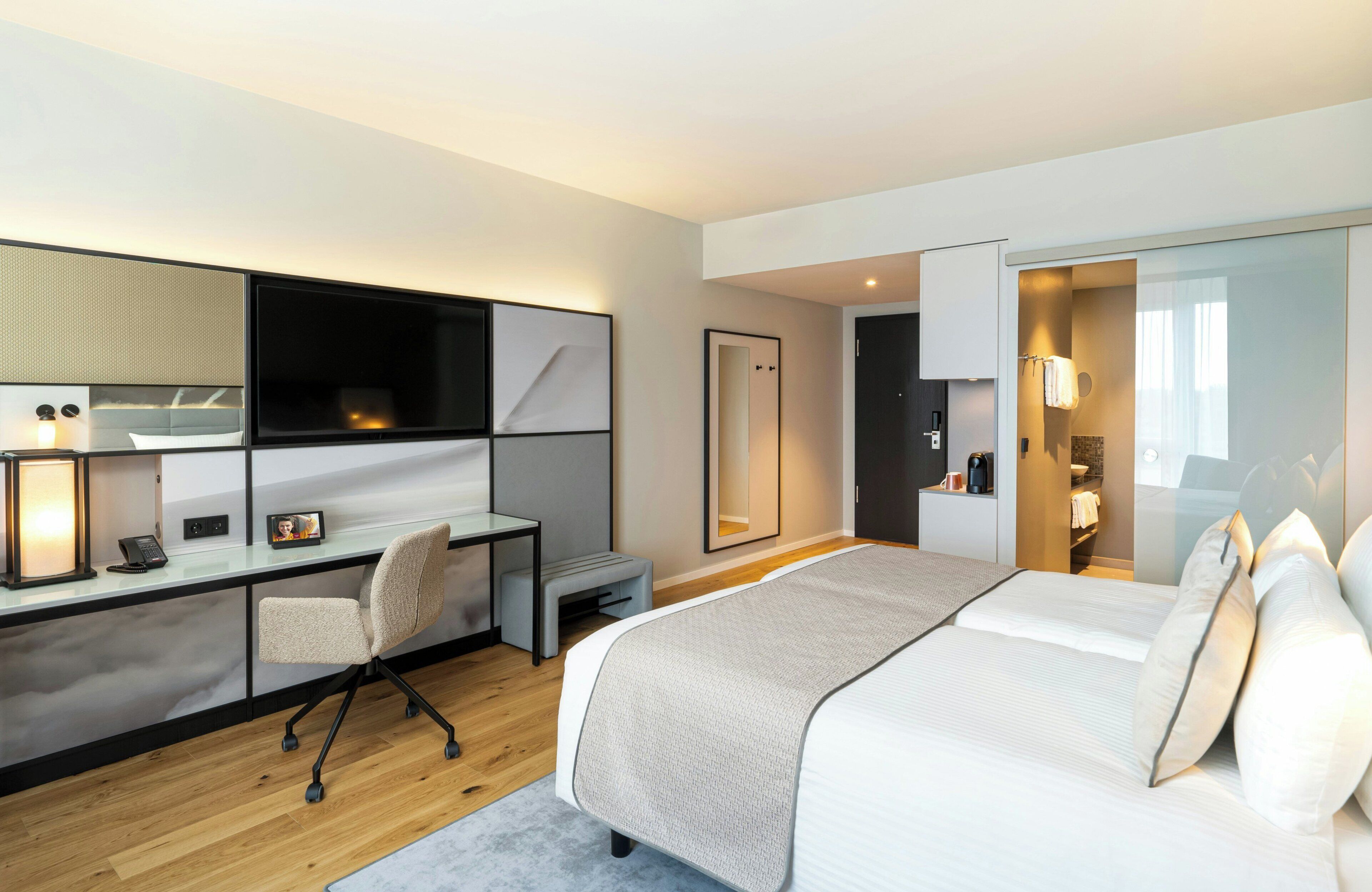 Quarto de hotel moderno com cama, escrivaninha, cadeira e closet espaçoso.