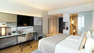 A modern hotel room with a bed, desk, chair, and a walk-in closet.