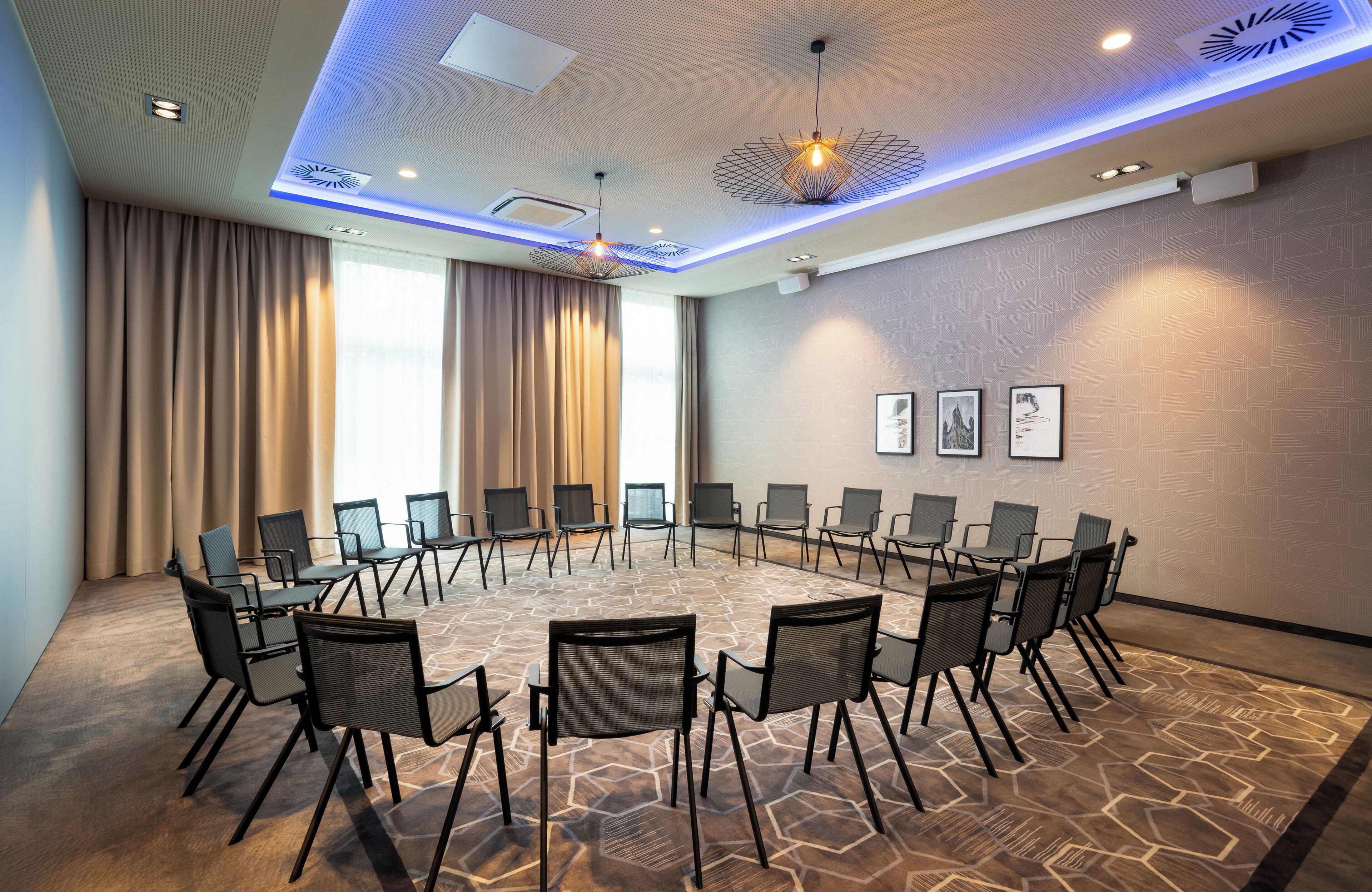 A conference room with a round table, chairs, and a patterned carpet.