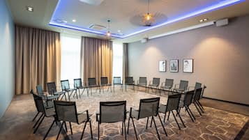 A conference room with a round table, chairs, and a patterned carpet.