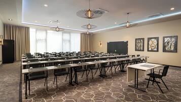A conference room with multiple tables, chairs, and a projector screen.