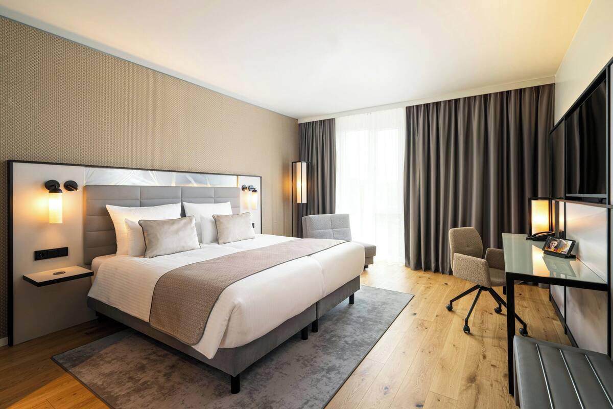 Una habitación de hotel moderna con una cama grande, mesitas de noche, un escritorio y una silla.