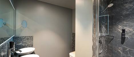 A modern bathroom with two sinks, a toilet, and a shower area with a glass door.