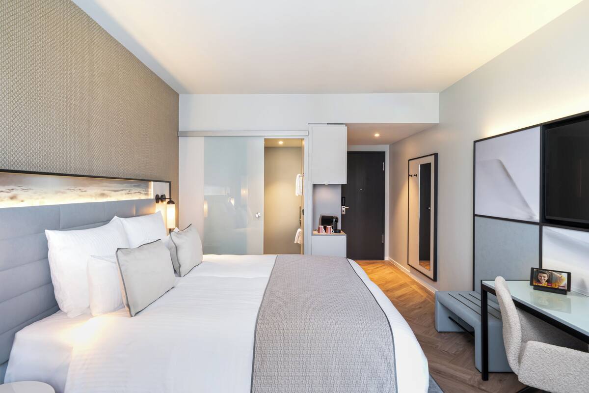 Una habitación de hotel moderna con una cama grande, un escritorio y un televisor.