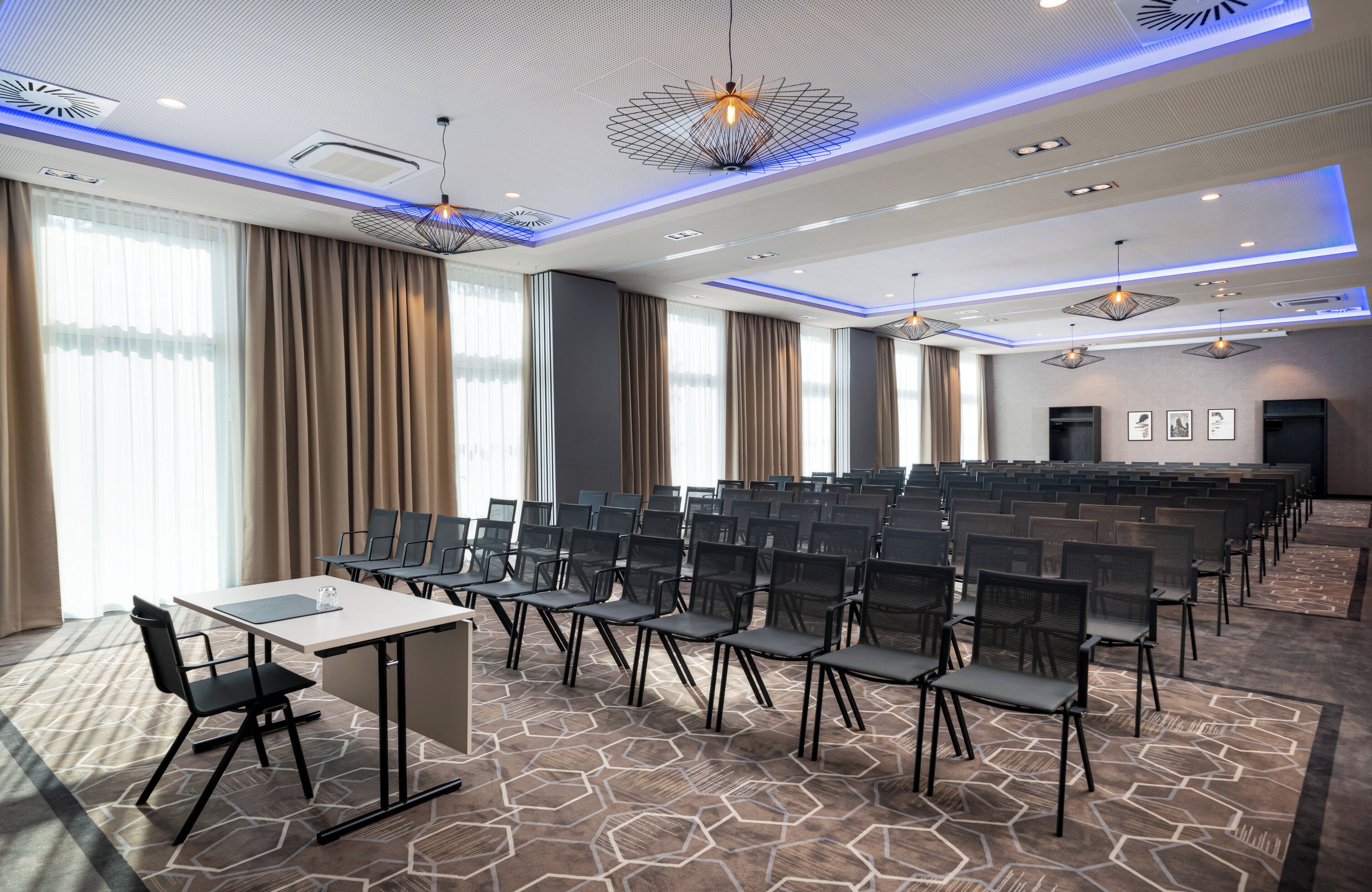 A conference room with rows of chairs, a table, and a stage.