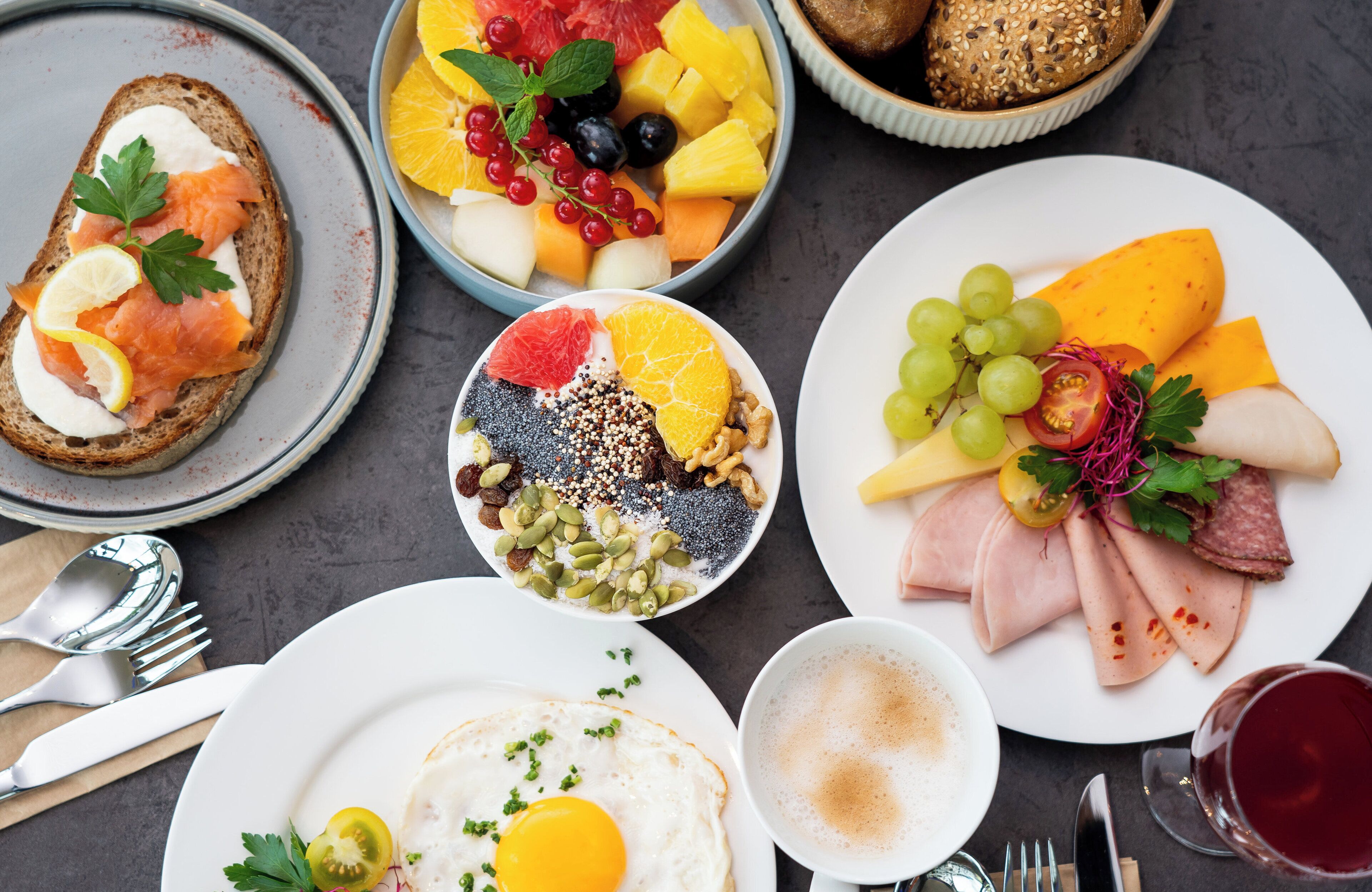 Una escena de desayuno con diversos platos, como tostadas, fruta, queso y embutidos.