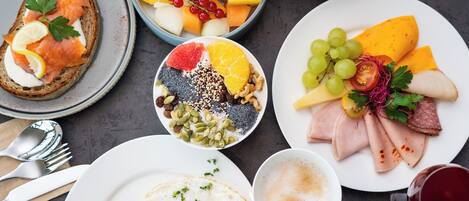 Una escena de desayuno con diversos platos, como tostadas, fruta, queso y embutidos.