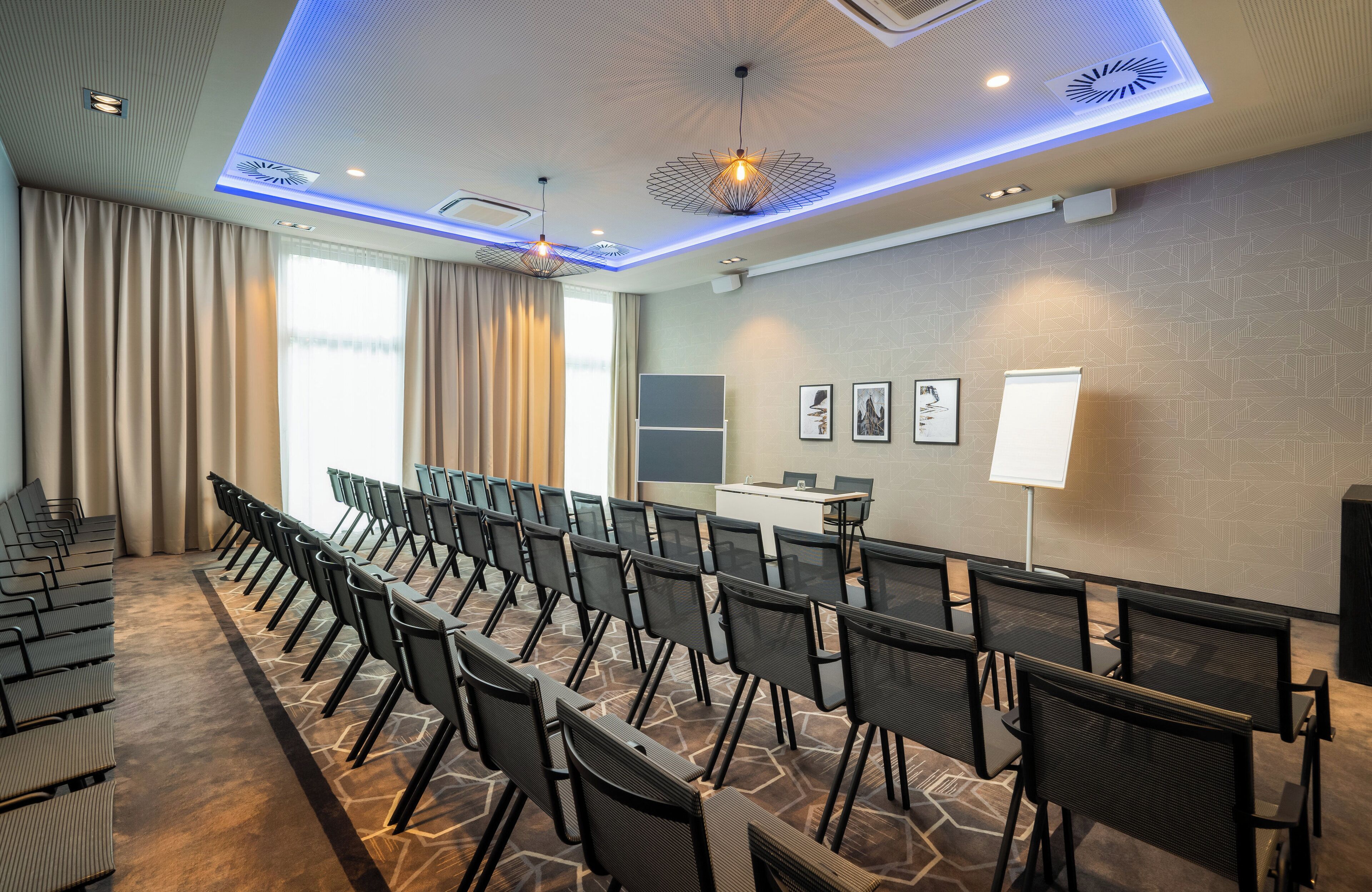 A conference room with rows of chairs, a podium, and a large window with curtains.