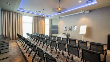 A conference room with rows of chairs, a podium, and a large window with curtains.