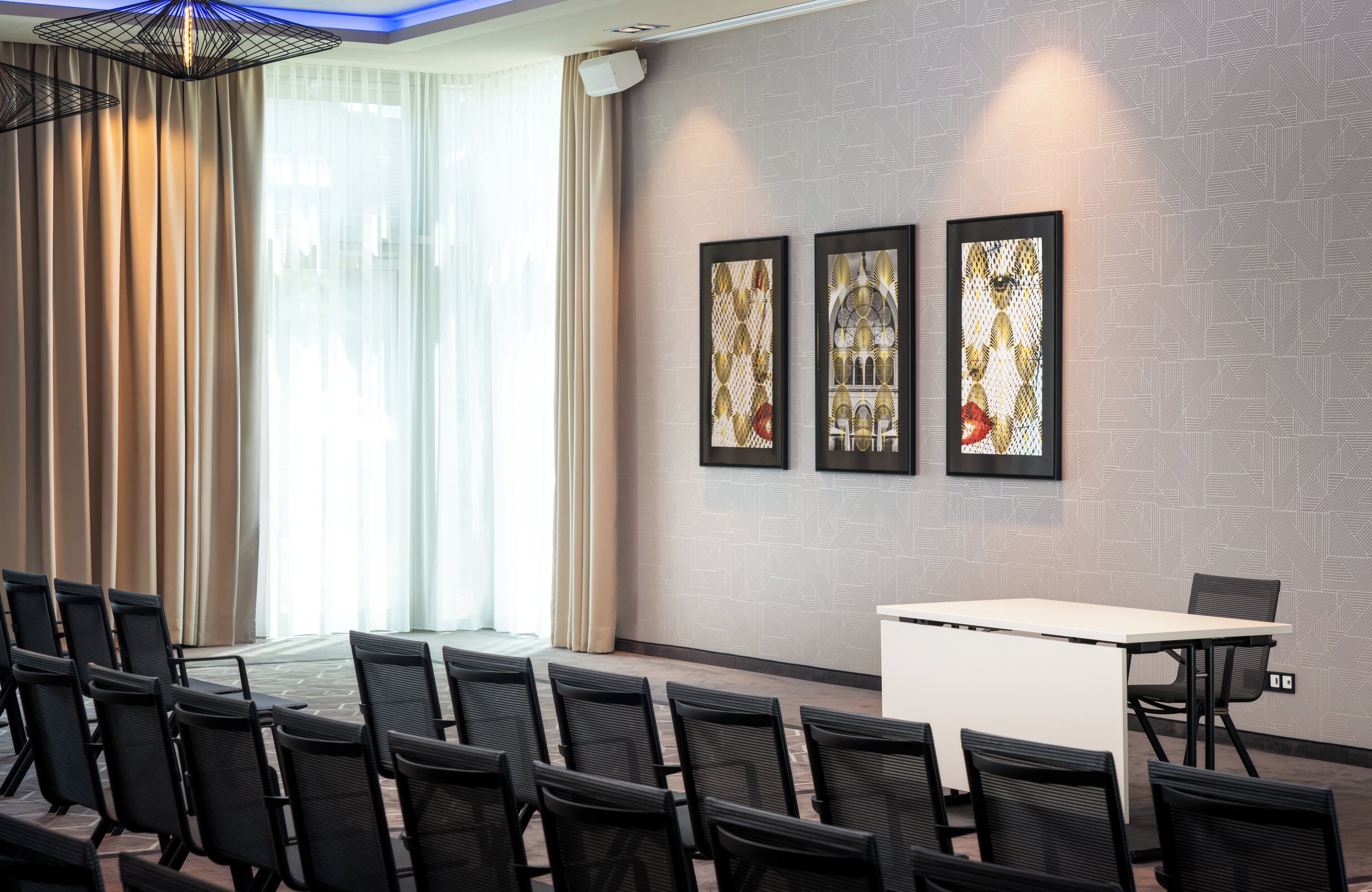 A conference room with a long table, chairs, and three framed artworks on the wall.