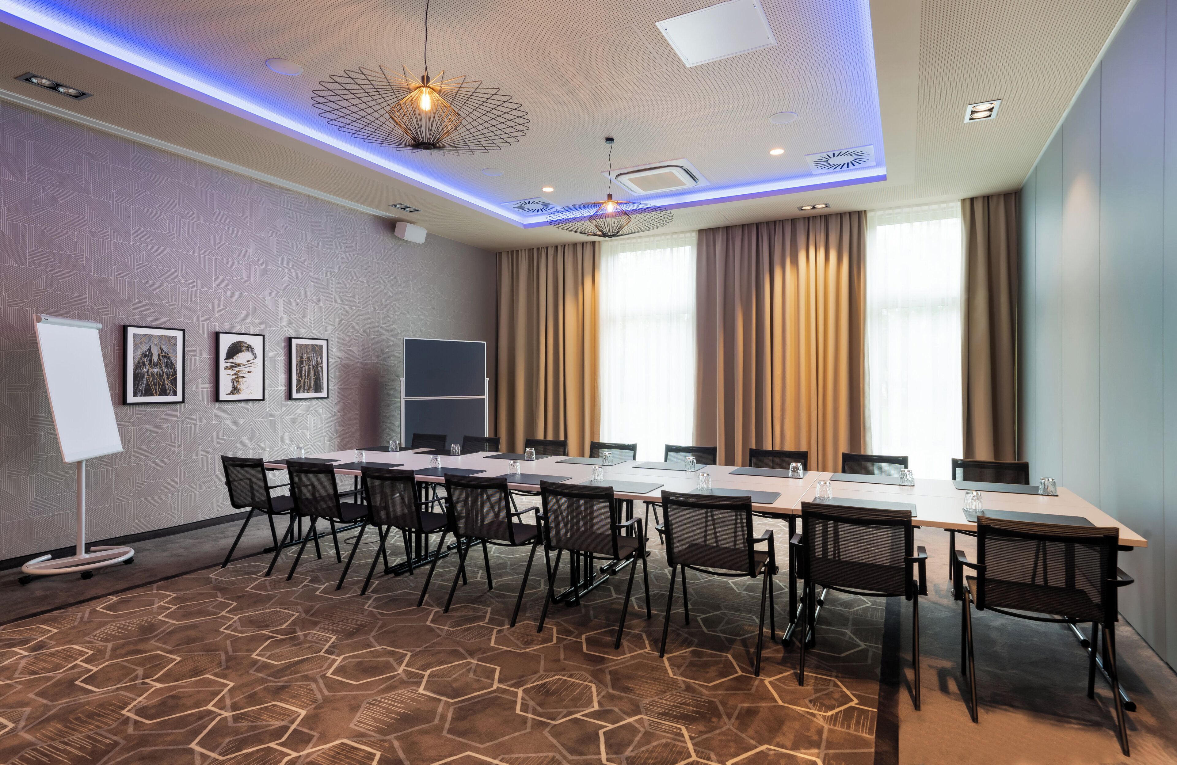 A conference room with a long table, chairs, a whiteboard, and framed pictures on the wall.