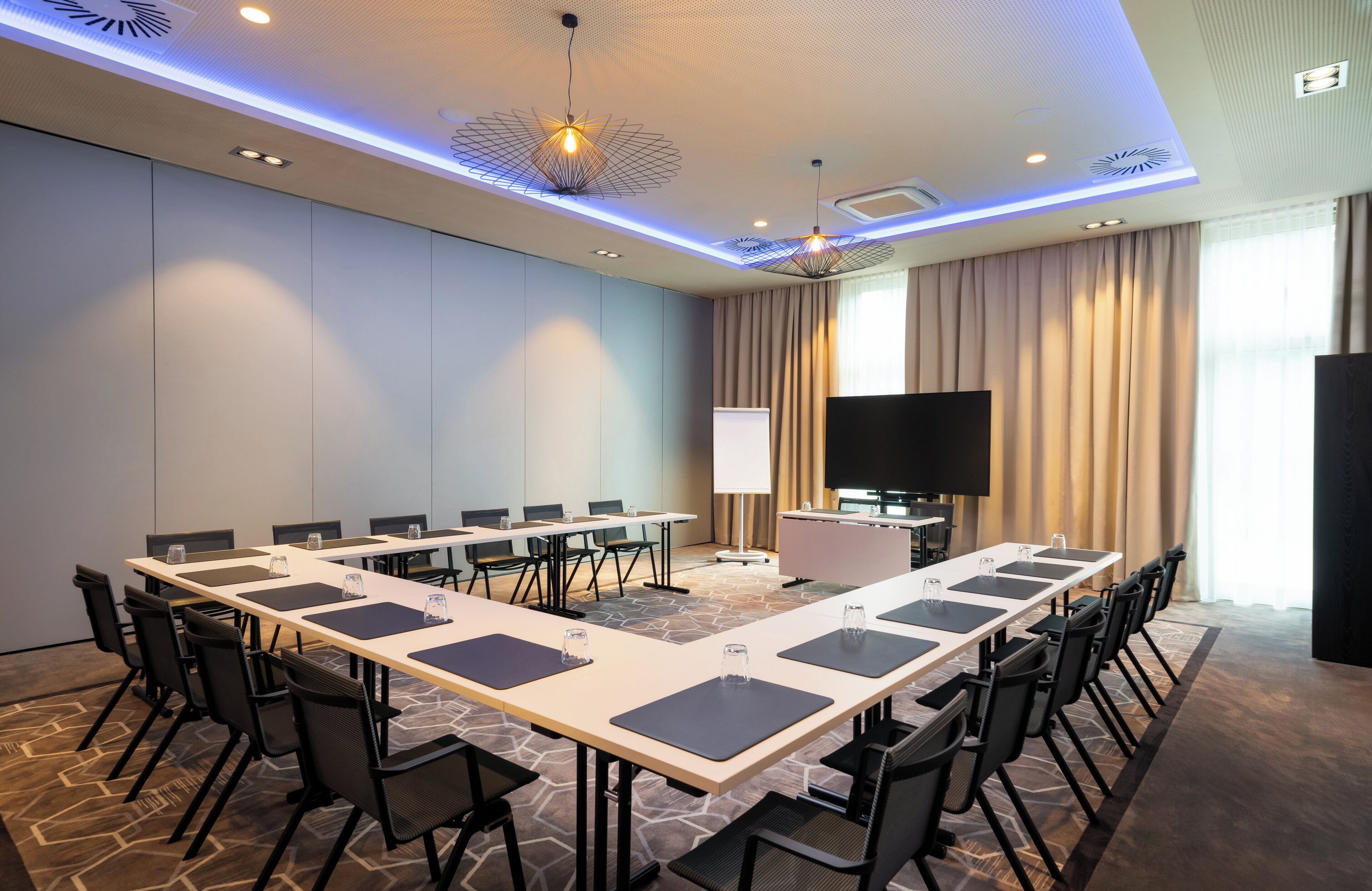 A conference room with a long table, chairs, a TV, and a whiteboard.