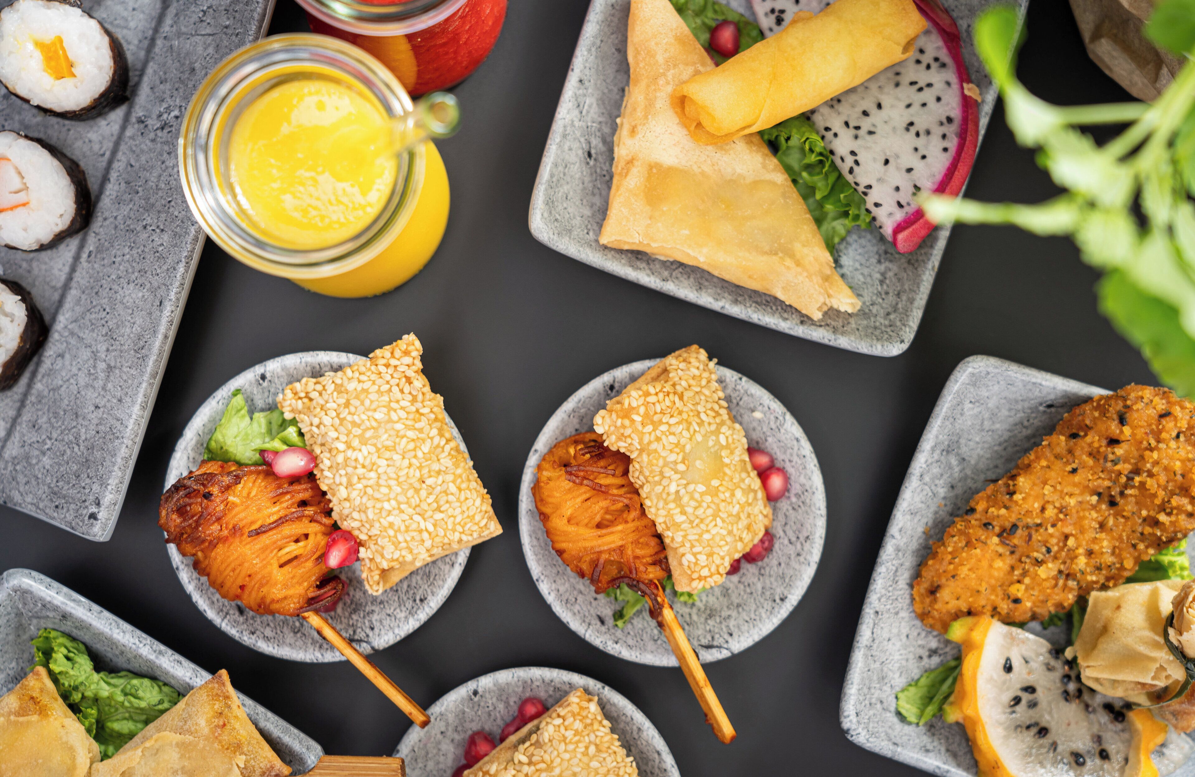 Un assortiment de plats comprenant des sushis, des fritures et une salade aux graines de sésame.