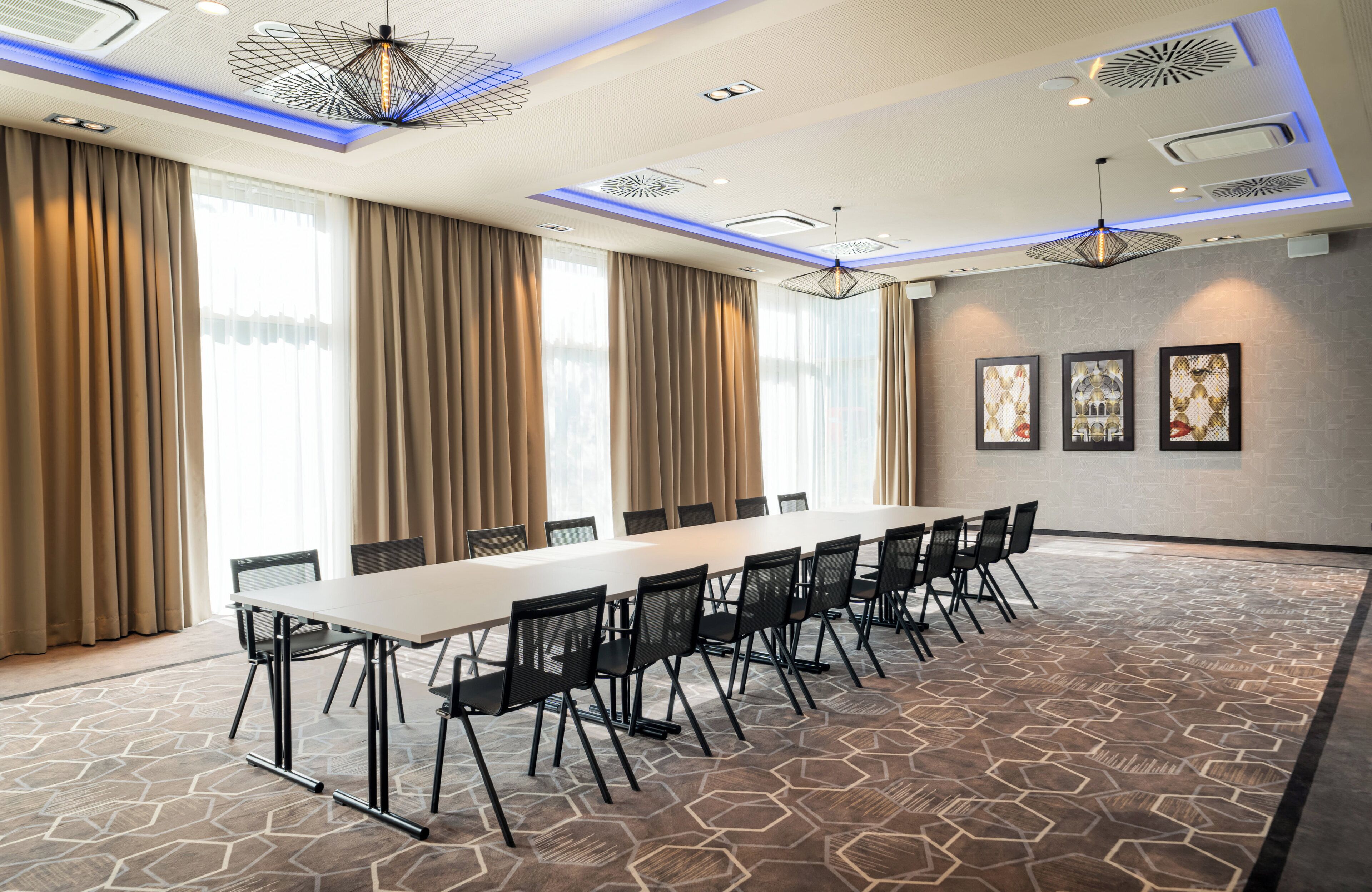 A conference room with a long table, chairs, and a patterned carpet.