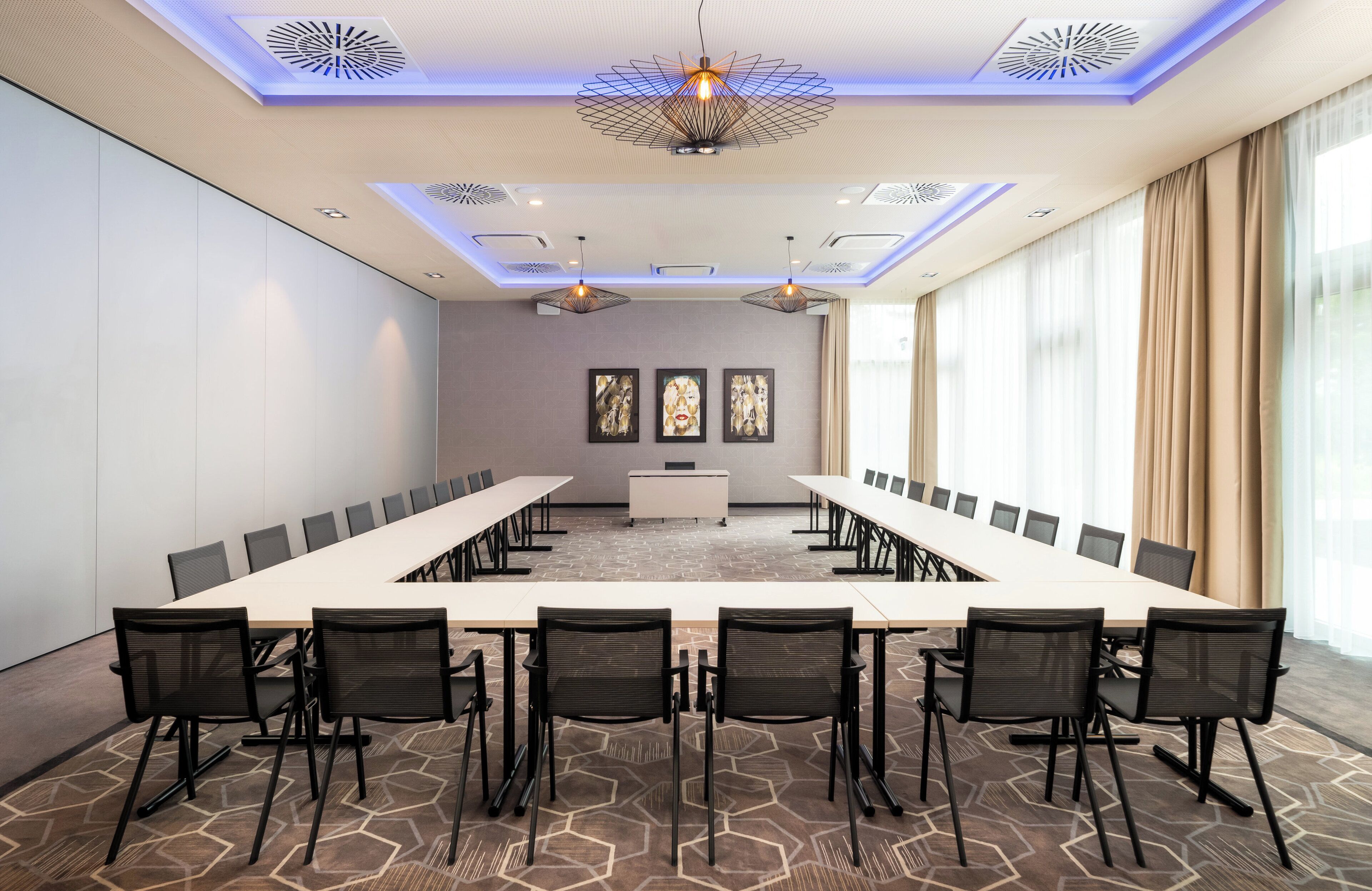 Ein Konferenzraum mit einem langen Tisch, schwarzen Stühlen und einer Wandtafel.