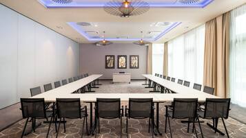 Une salle de conférence avec une longue table, des chaises noires et un tableau blanc.