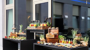 A buffet setup with various food items and drinks, arranged on tables outside a building. - Leonardo Royal Hotel Cologne Bonn Airport (Cologne)