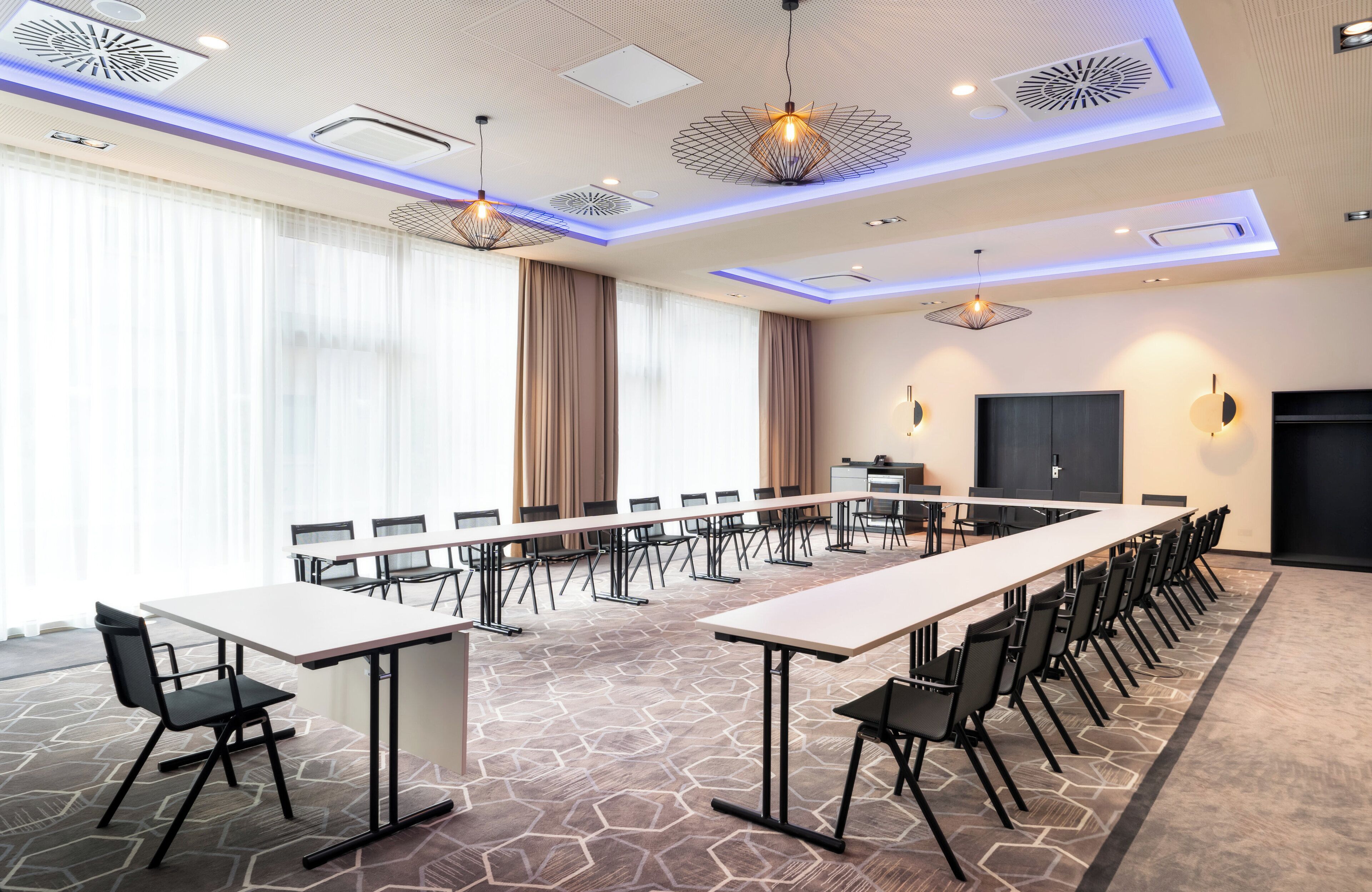 A conference room with a long table, chairs, and a projector screen.