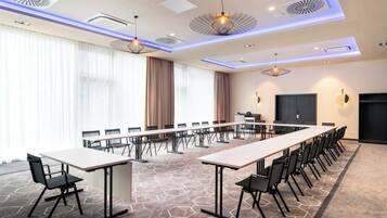 A conference room with a long table, chairs, and a projector screen.