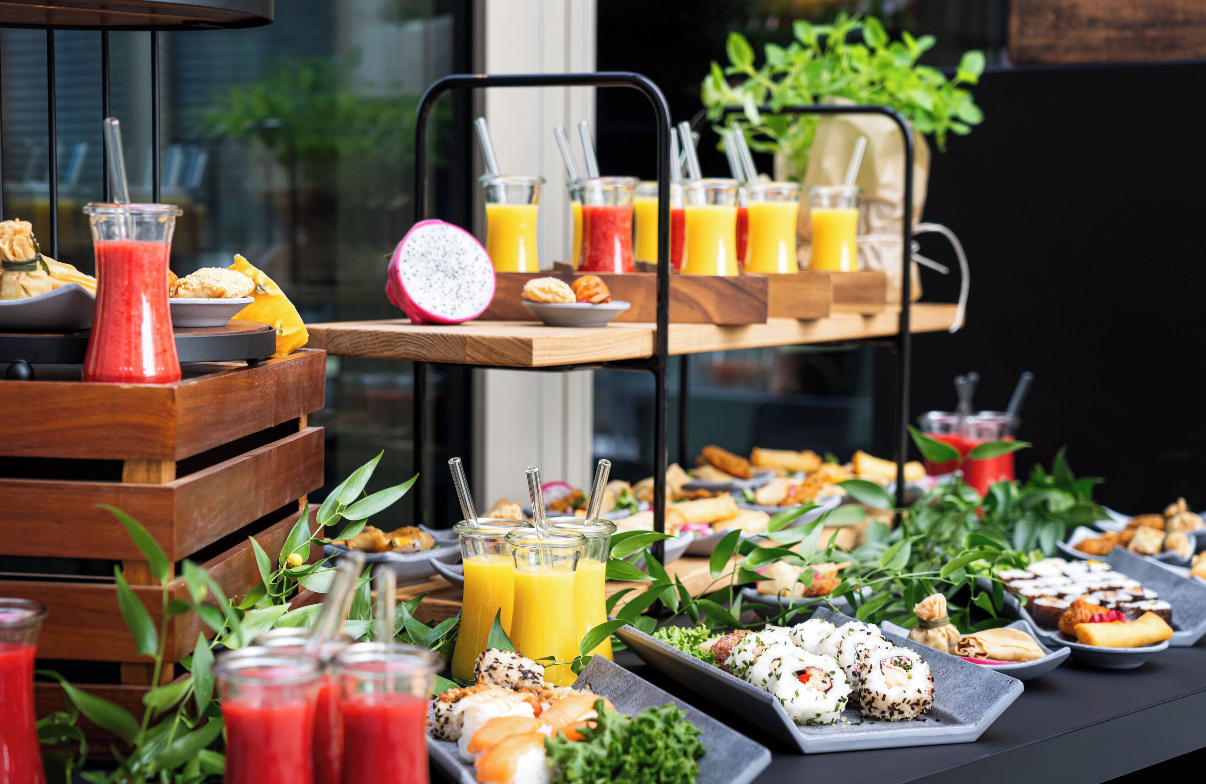 Monipuolinen buffet, jossa on tarjolla erilaisia ruokia ja juomia, kuten lohikäärmeen hedelmää ja valikoima mehuja.