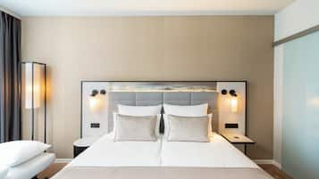 Una habitación de hotel moderna con una cama grande, dos mesitas de noche y un cabecero con iluminación integrada.