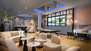 A modern lounge area with a pool table, comfortable seating, and a large window with a city view. - Leonardo Royal Hotel Cologne Bonn Airport (Cologne)