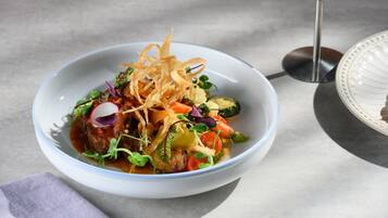 A bowl of food with various vegetables and garnishes.
