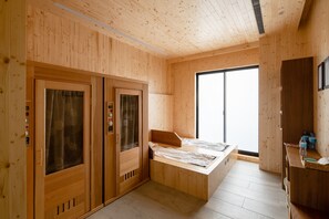 Une pièce en bois avec un lit, une porte coulissante et une grande fenêtre.