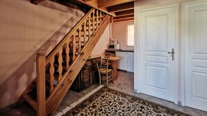 Una escalera de madera con un tapete estampado que lleva a una zona de cocina con microondas y cafetera.
