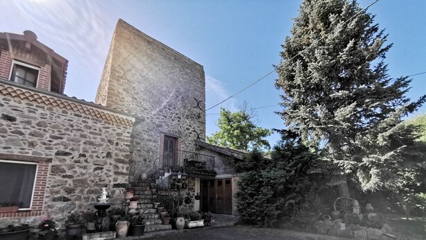 Un edificio de piedra con puerta de madera y un pequeño balcón.