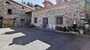 Un patio con edificios de piedra, una puerta de madera y plantas en macetas.