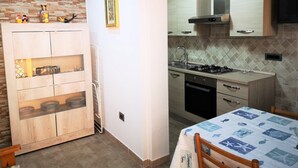 Une cuisine de taille réduite, équipée d’une cuisinière à gaz, d’un évier et de meubles de rangement en bois.
