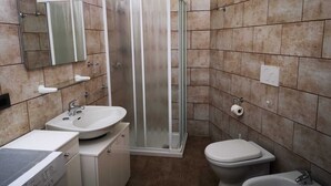 Une salle de bain équipée d’une douche, de toilettes, d’un bidet, d’un lavabo et d’un lave-linge.