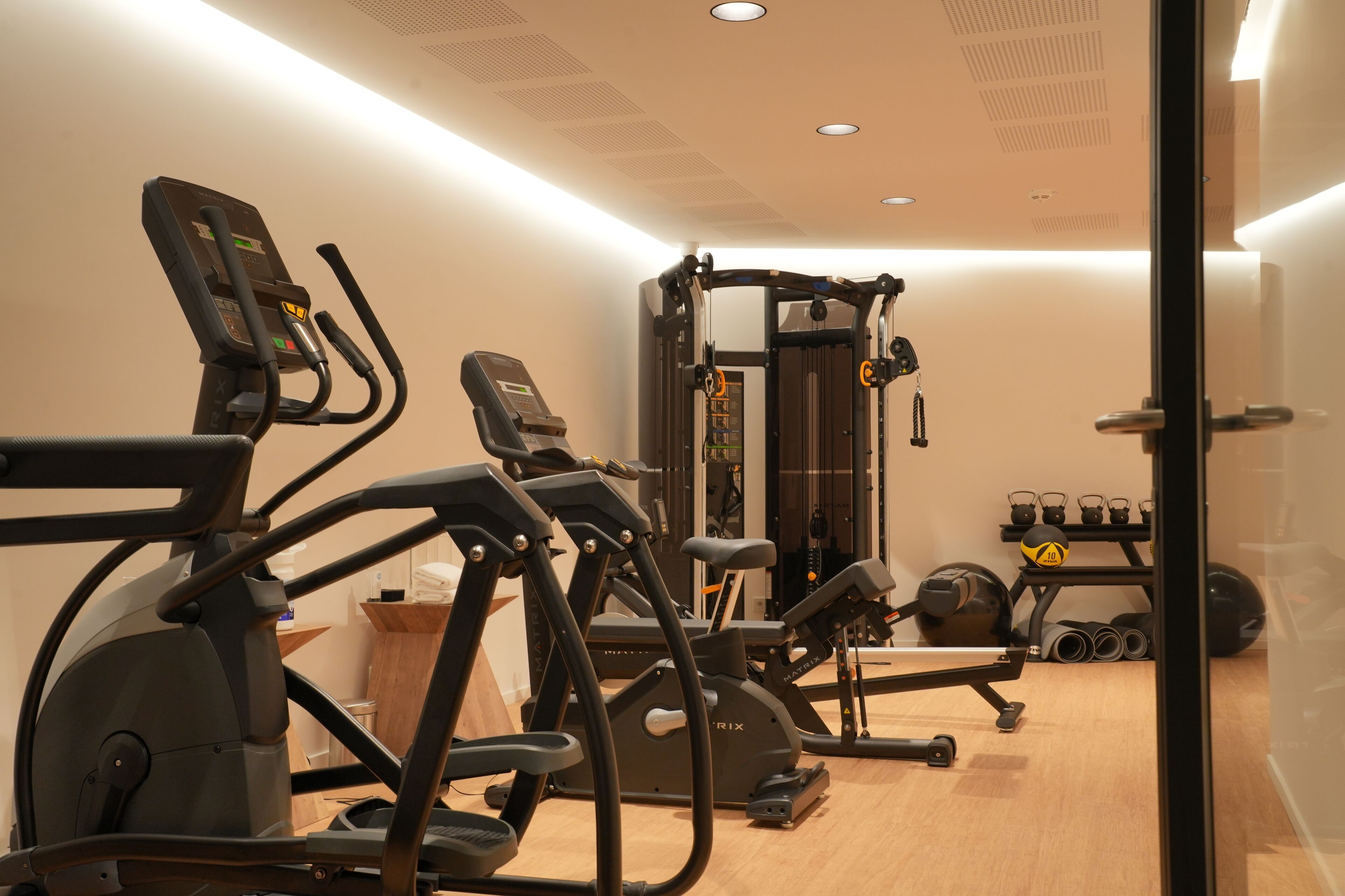 A modern gym with cardio machines, weightlifting equipment, and a mirror.
