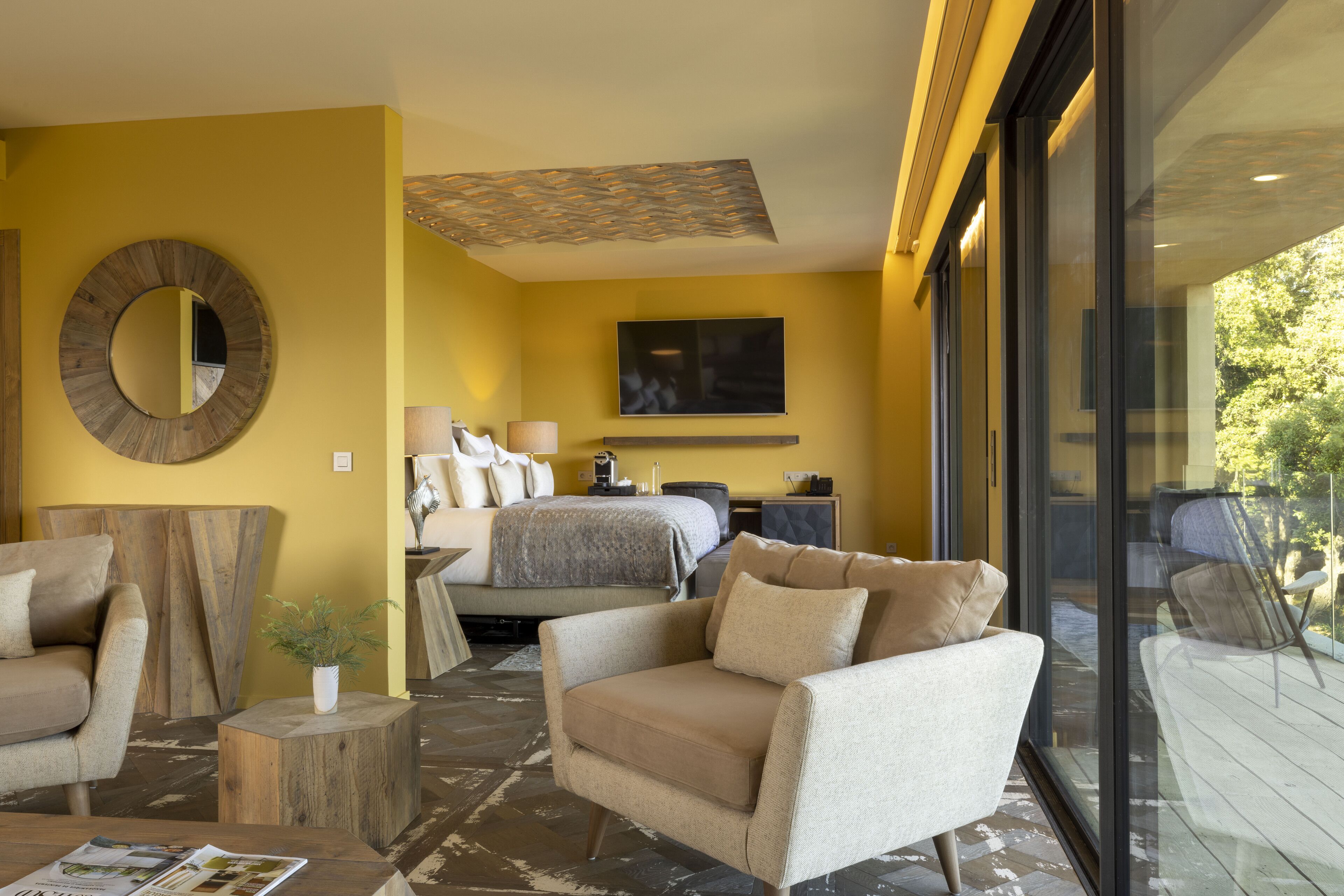 Ein modernes Hotelzimmer mit einem großen Bett, einer Couch, einem Couchtisch und einem an der Wand befestigten Fernseher.