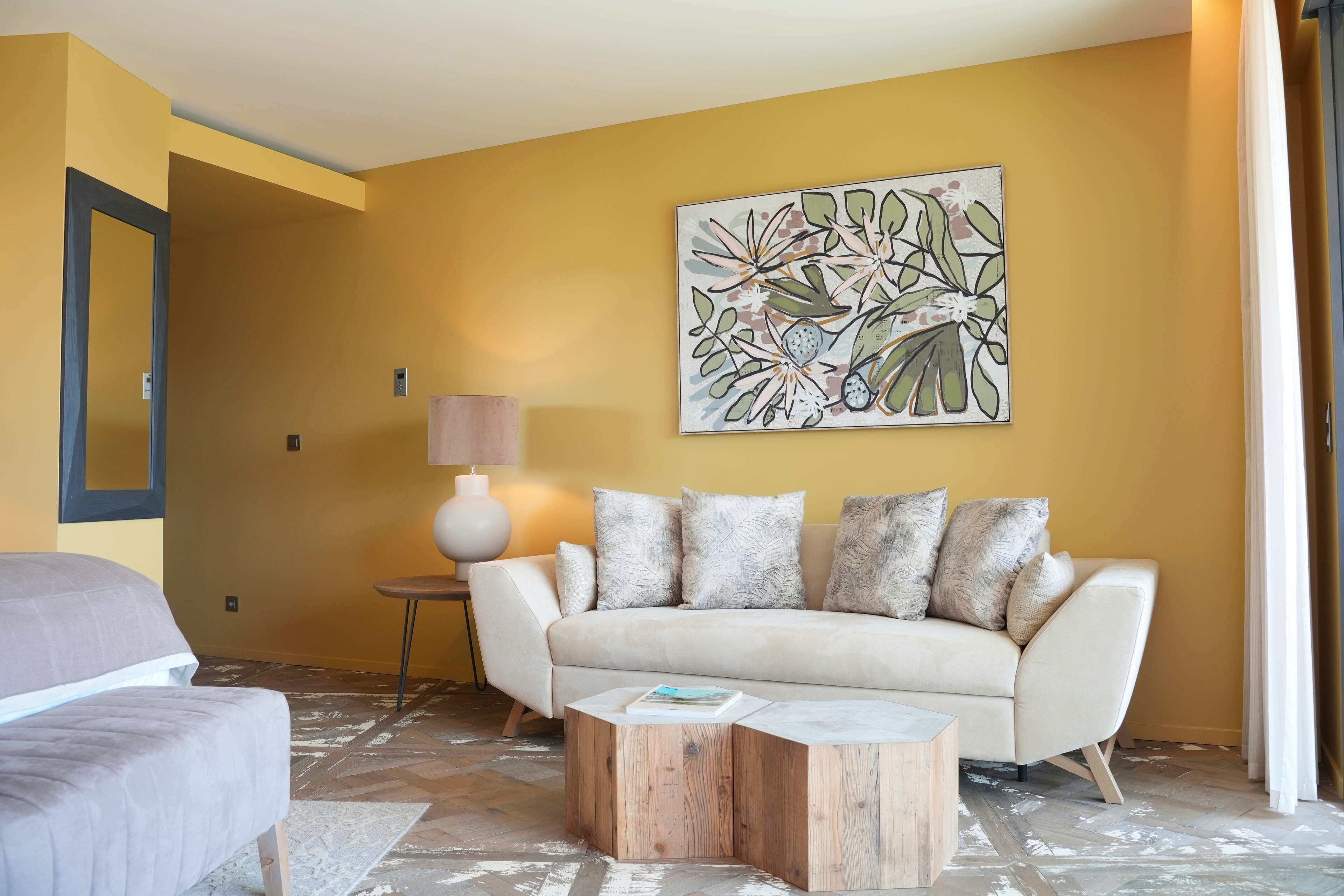 A living room with a sofa, a coffee table, and a painting on the wall.