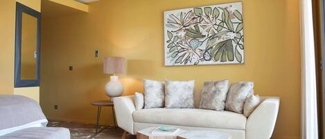 A living room with a sofa, a coffee table, and a painting on the wall.