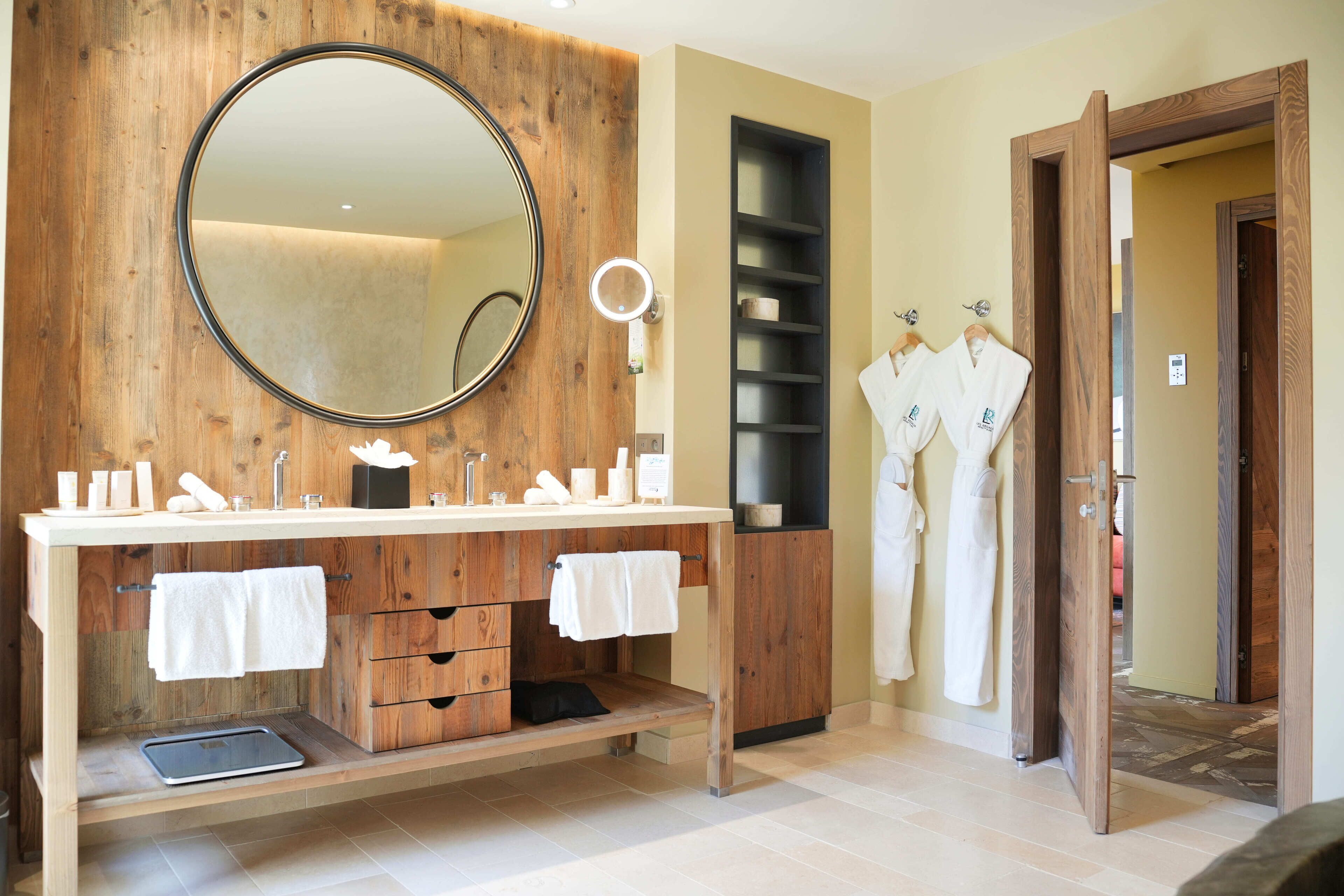 A modern bathroom with wooden cabinetry, a large mirror, and a vanity with multiple sinks.