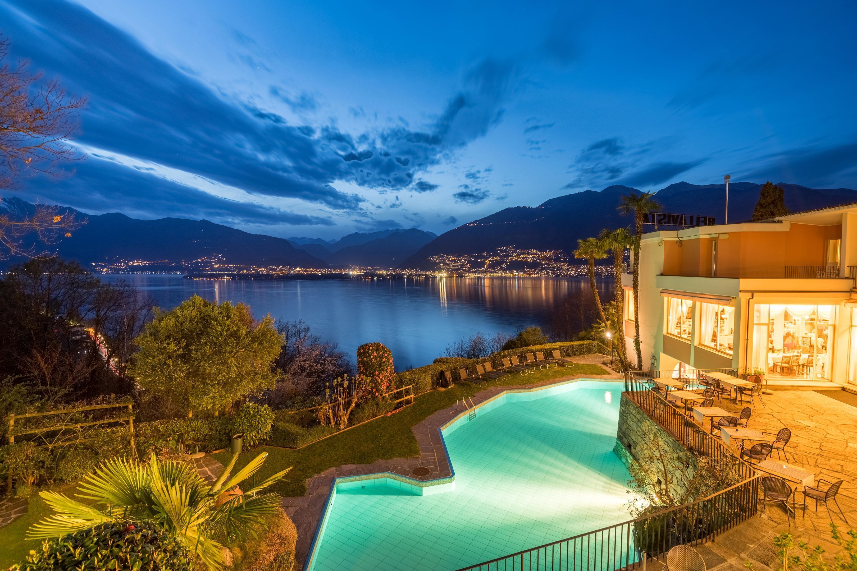 A swimming pool with a view of a city and mountains in the background.