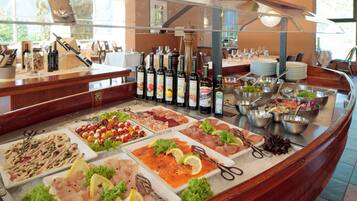 A buffet with various food items and a selection of wines.