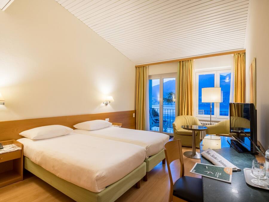 Habitación de hotel con dos camas, un escritorio, una silla, un televisor y vista al mar.