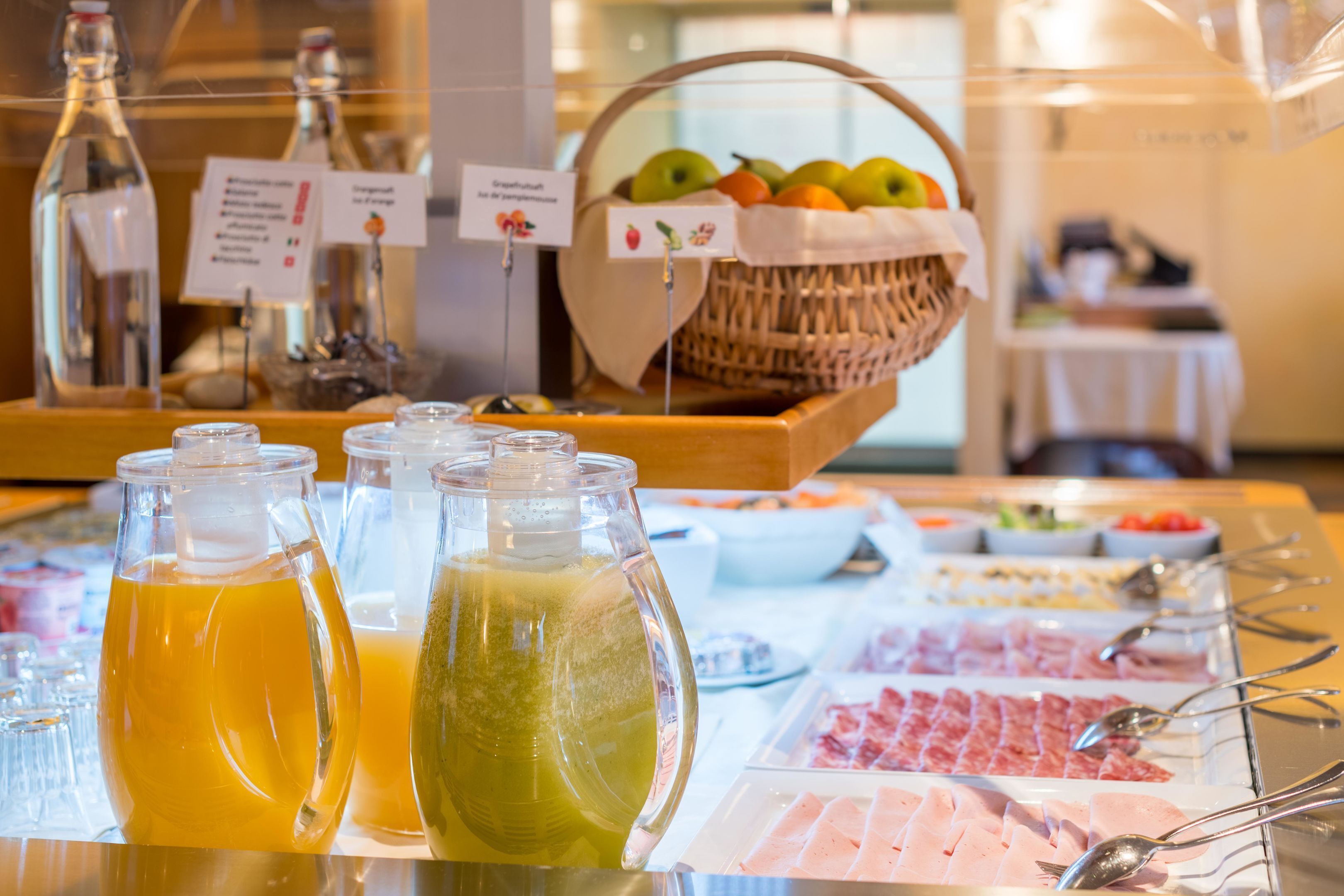 Un bufé con diversas opciones de comida, incluyendo frutas, carnes y bebidas.