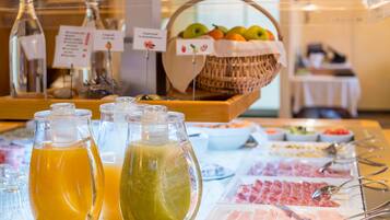 Un bufé con diversas opciones de comida, incluyendo frutas, carnes y bebidas.