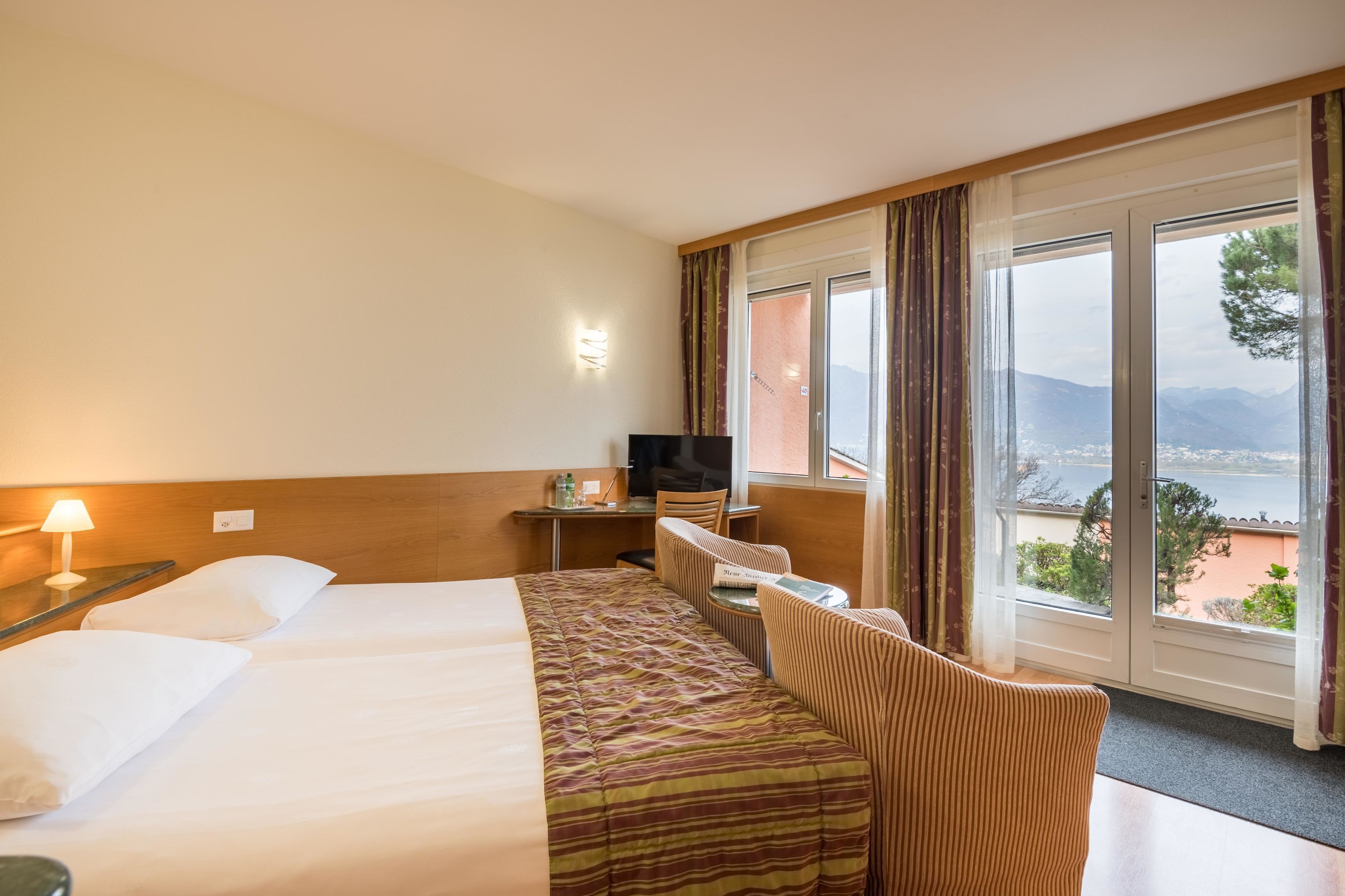 A hotel room with a bed, a desk, a chair, and a TV.